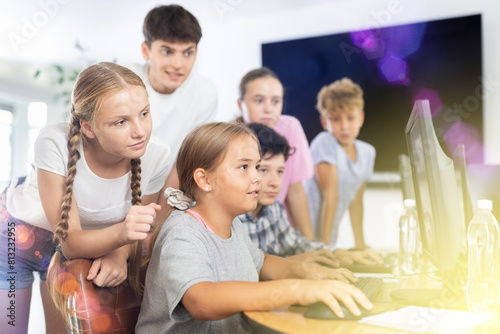 Computer lesson in classroom - classmates solve problems on the computer together