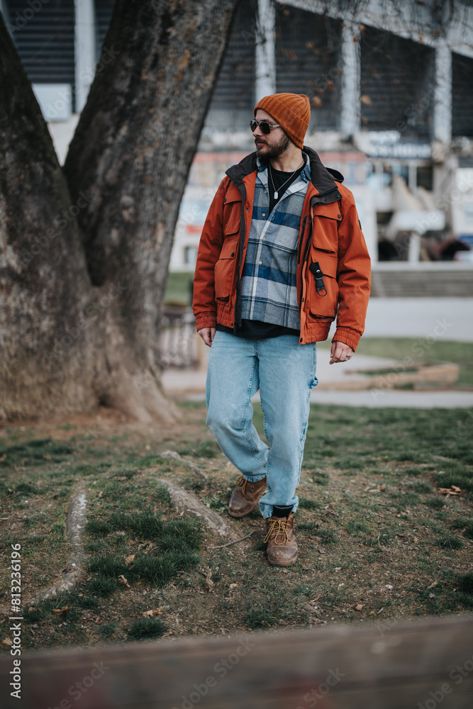 A trendy man with sunglasses and a beanie walks in a park, showcasing winter fashion with a confident stance. A trendy man with sunglasses and a beanie walks in a park, showcasing winter fashion with a confident stance.