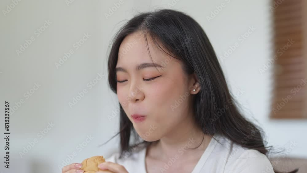 Closeup young woman eating burger at home Closeup young woman eating burger at home