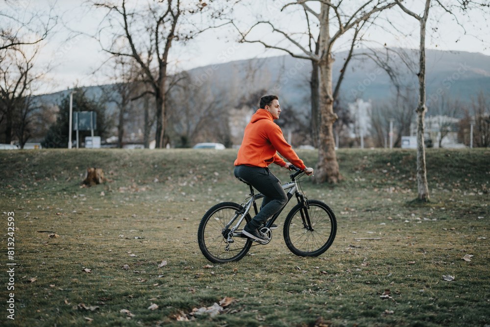 A young man rides a bicycle in an urban park, enjoying the weekend with a relaxing outdoor activity, promoting fitness and well-being.