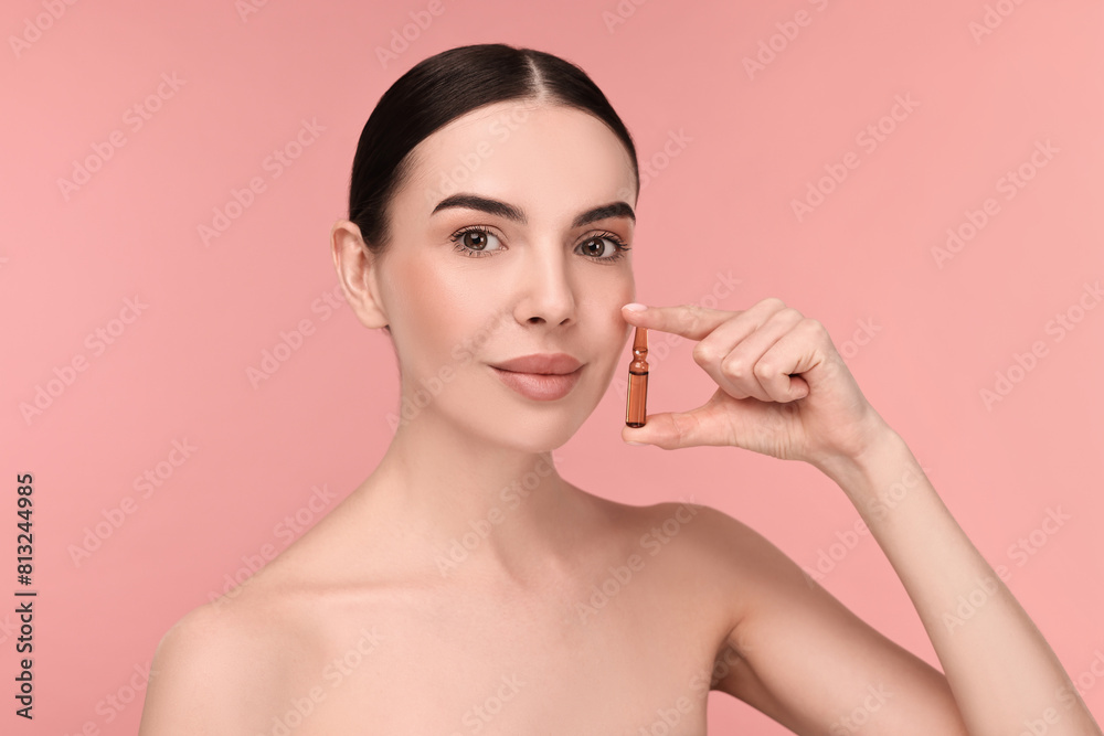 Beautiful young woman holding skincare ampoule on pink background Beautiful young woman holding skincare ampoule on pink background