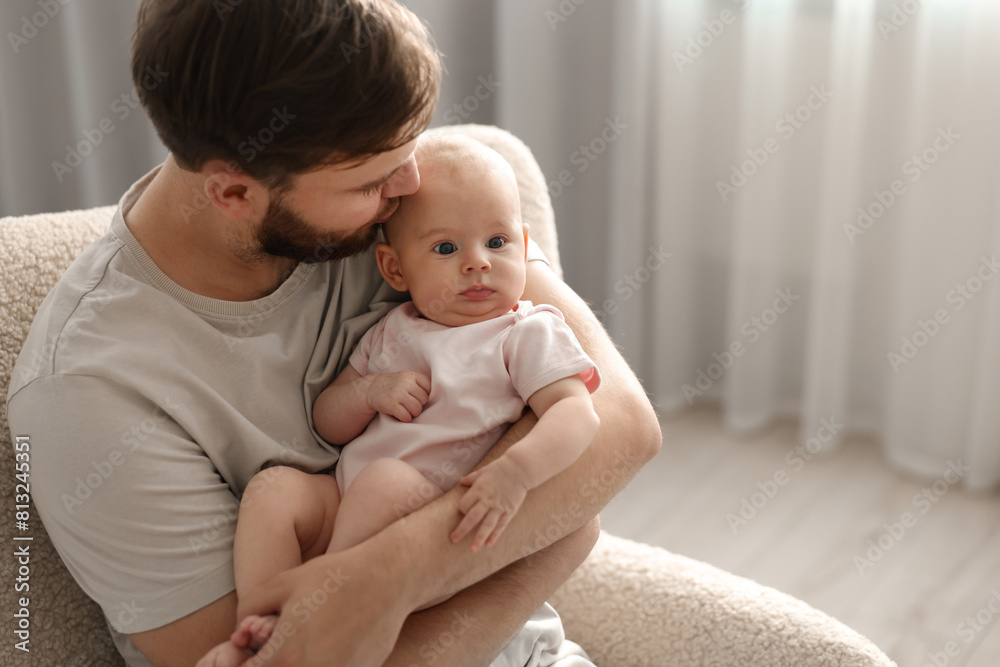 Father with his cute baby in armchair at home, space for text Father with his cute baby in armchair at home, space for text