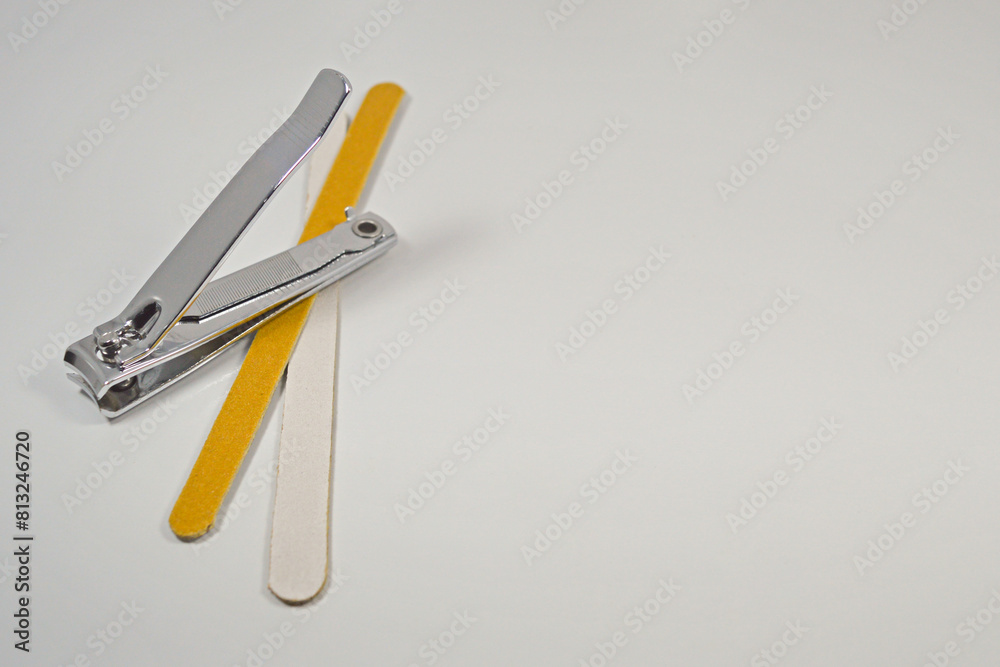 Isolated nail clipper and a pair of nail files placed on the left side of a white background.