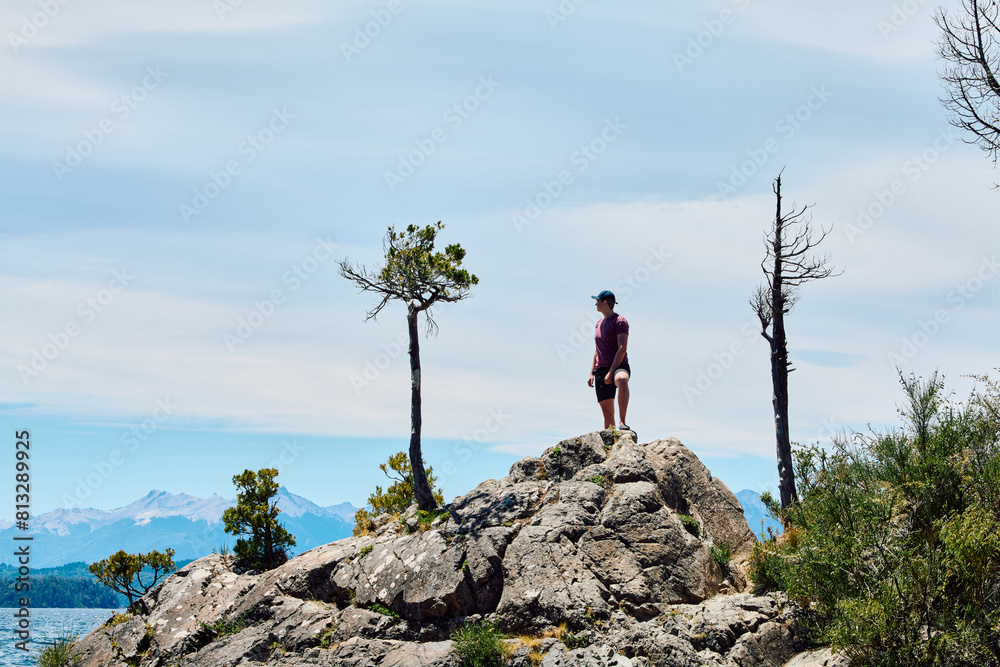 Obraz premium a young man standing on the top of a rock symbolizing unity with nature and the desire to conquer new heights