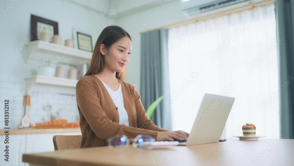 Beautiful young Asian woman working with laptop computer in home kitchen. Work at home Beautiful young Asian woman working with laptop computer in home kitchen. Work at home