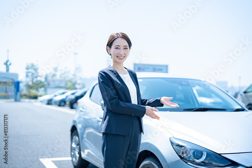 Obraz na płótnie 屋外に停めてある車の前に立つスーツを着た女性