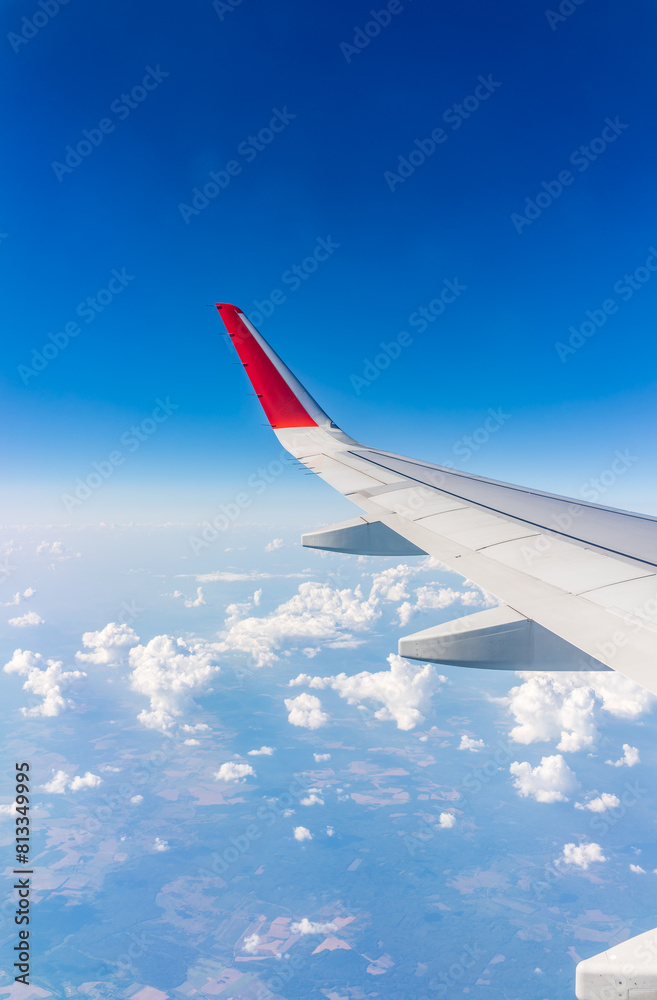 Fototapeta premium View from the airplane window at a beautiful cloudy sky and the airplane wing