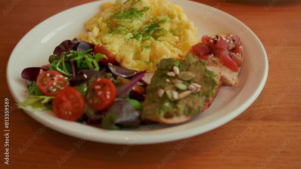 A nutritious brunch serving with fluffy scrambled eggs, a vibrant mixed salad, avocado toast, and seeds. A nutritious brunch serving with fluffy scrambled eggs, a vibrant mixed salad, avocado toast, and seeds.