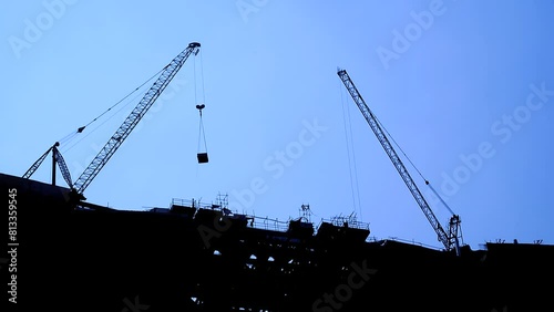 Silhouette of a crane doing construction work with crane movement. clear blue sky elapsed time.
 photo