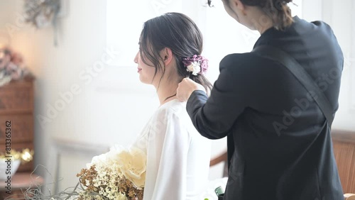 Video of bride and hair and makeup artist preparing for wedding hair set and pre-wedding shoot in a beautifully backlit room.