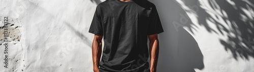 An oversized black tshirt on a minimalist white wall, perfect for graphic design mockups