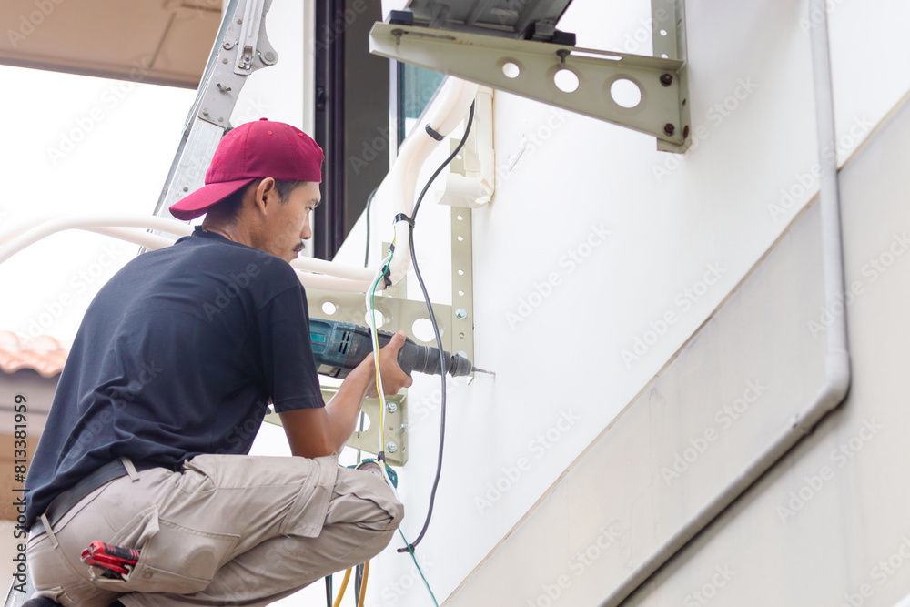 Technician man with hammer drill installing an air conditioning, Repairman service for repair and maintenance of air conditioners Technician man with hammer drill installing an air conditioning, Repairman service for repair and maintenance of air conditioners