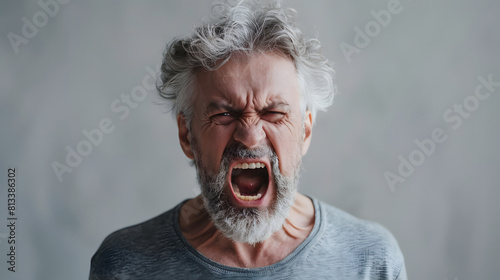 Close-up of an elderly man with a beard, yelling intensely with a furious expression. Perfect for themes related to anger, emotion, and intensity. photo