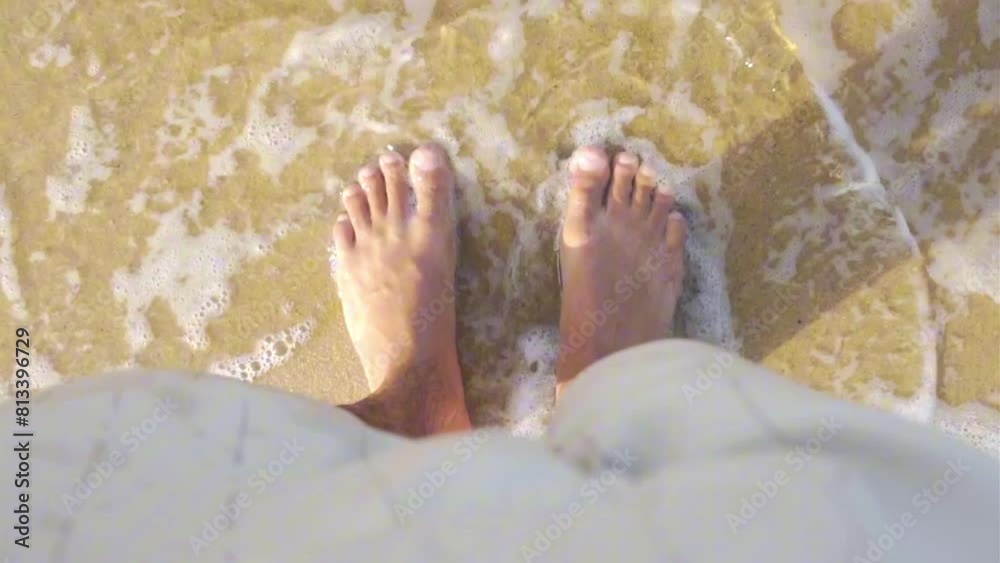 Small sea wave coming on the feet in slow motion, feet on the sand, top down view Small sea wave coming on the feet in slow motion, feet on the sand, top down view