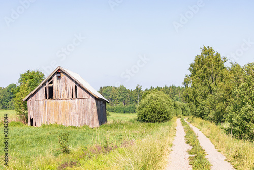 Old barn in bad condition by a dirt road in a rural landscape