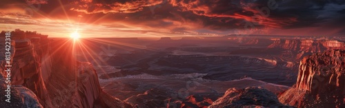 The sun is setting over a jagged mountain range  casting a warm orange glow across the landscape. Silhouettes of peaks are visible against the colorful sky as the day transitions to night.