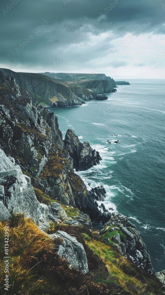 A rocky cliff juts out over the ocean, under a cloudy sky. The waves crash against the base of the cliff, creating a dramatic scene of natures power and beauty. A rocky cliff juts out over the ocean, under a cloudy sky. The waves crash against the base of the cliff, creating a dramatic scene of natures power and beauty.