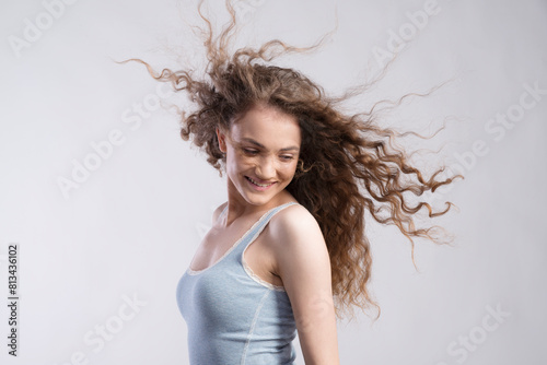 Portrait of a gorgeous teenage girl with flying curly hair, blowing in wind. Studio shot, white background with copy space photo