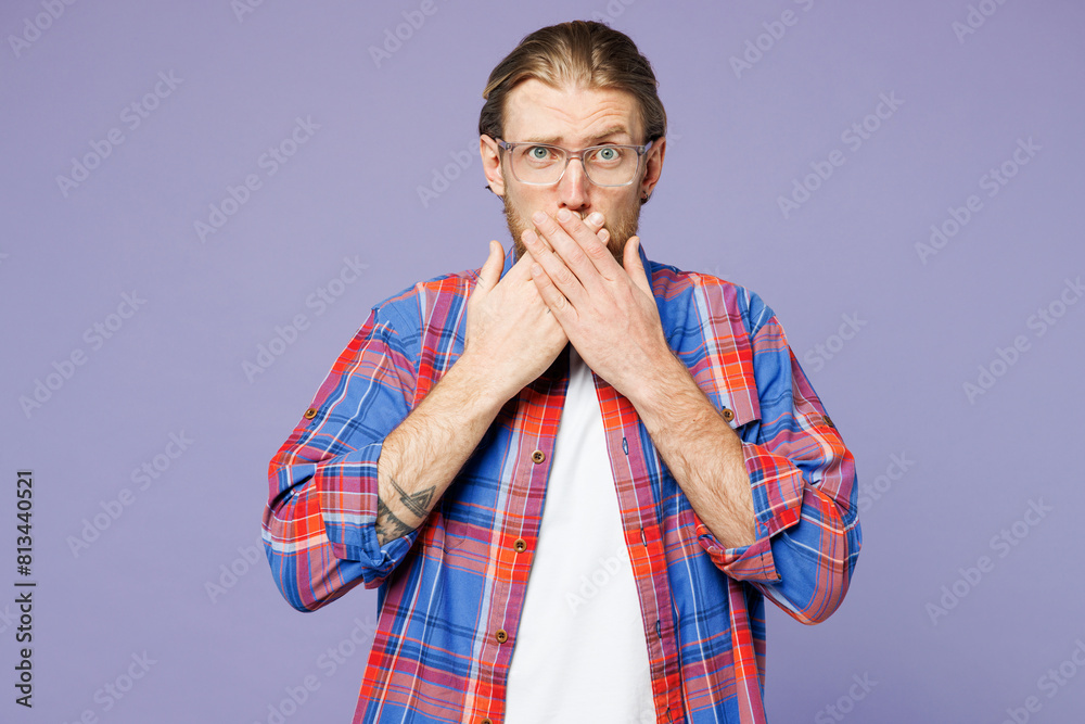 Young sad shocked surprised amazed man he wearing blue shirt casual clothes covering mouth with hand looking camera isolated on plain pastel light purple background studio portrait. Lifestyle concept. Young sad shocked surprised amazed man he wearing blue shirt casual clothes covering mouth with hand looking camera isolated on plain pastel light purple background studio portrait. Lifestyle concept.