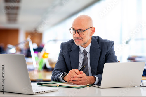 Businessman sitting at the office and looking at the computer thoughtfully