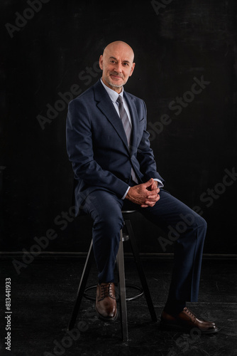 Full length shot of a mid aged businessman wearing suit against isolated dark background