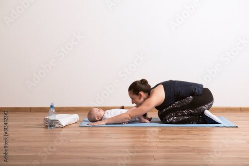 Home pilates exercise for mother and baby, mommy and me workout. Physical activity for mother while bonding with children.