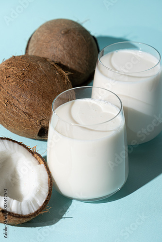 Coconut milk in a glasses among coconuts on a blue background