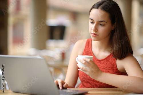 Serious woman is using laptop drinking coffee in a terrace © PheelingsMedia
