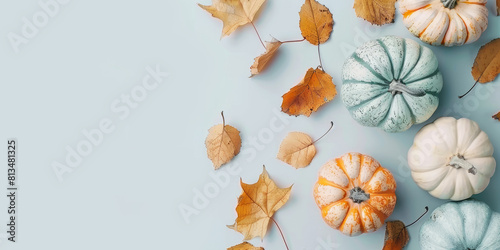 Bright orange leaves and pumpkins on a blue background. Autumn banner with copy space.