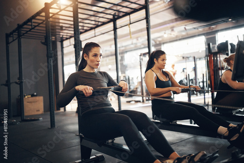 Fit group of young women in sportswear working out on rowing machines during an exercise class together in a gym