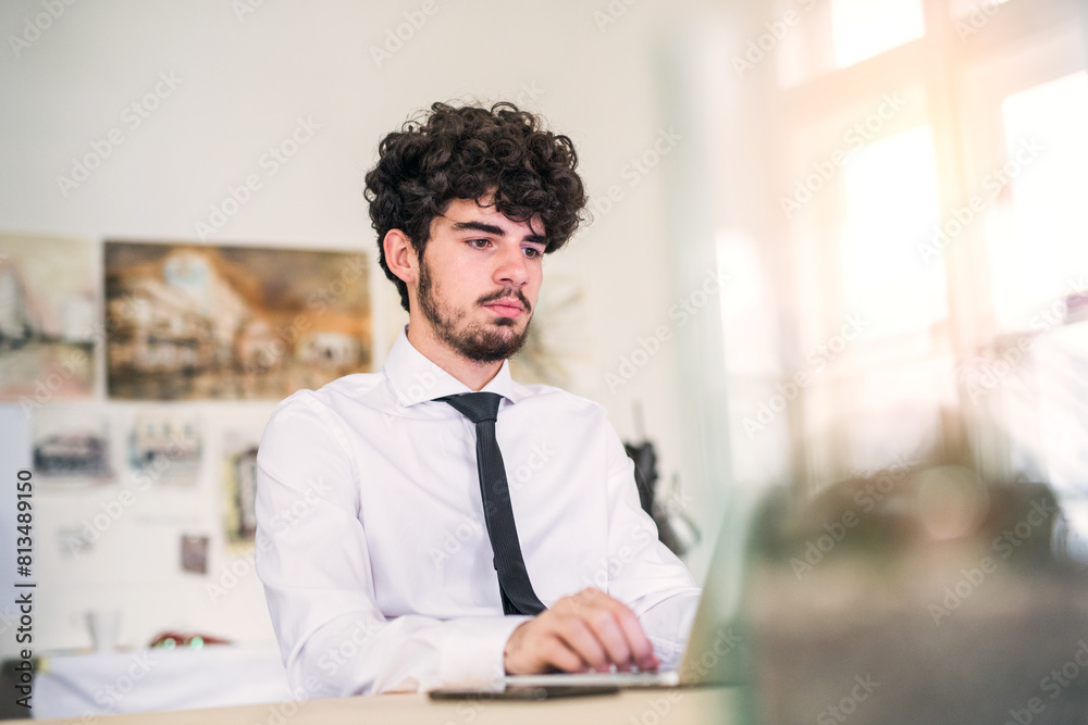 Fototapeta premium Young businessman working on new project in a startup company office. Working in co-working space.