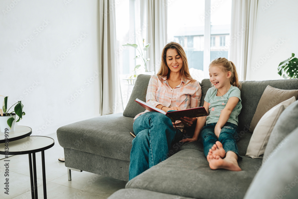 Smiling daughter and mother reading book at home Smiling daughter and mother reading book at home
