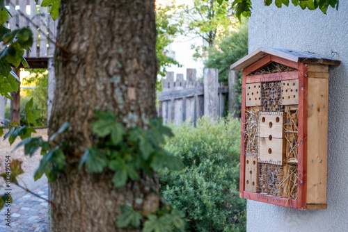 Insect hotel mounted on wall near tree photo