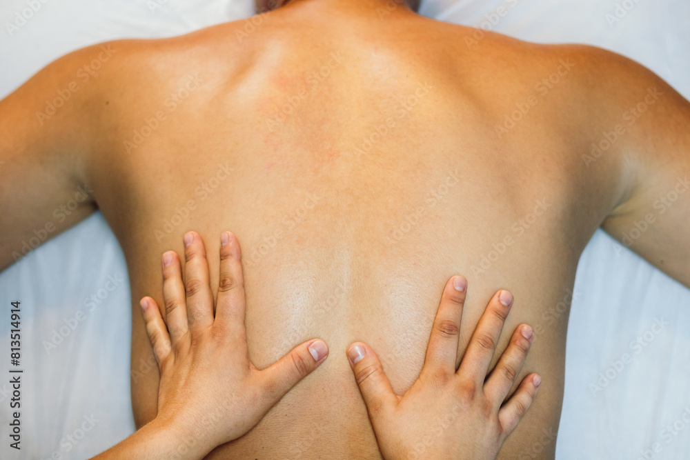 Fototapeta premium top view of a back massage. young woman hands treating male back. physiotherapist