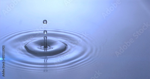 Image of water drops dropping into blue water with glowing light