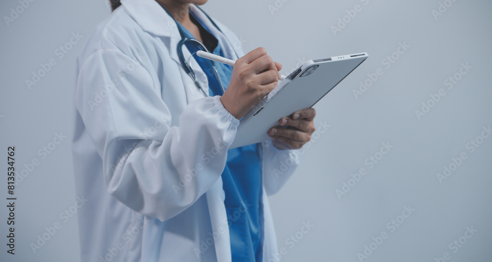 Woman doctor using tablet computer while standing straight in hospital Woman doctor using tablet computer while standing straight in hospital