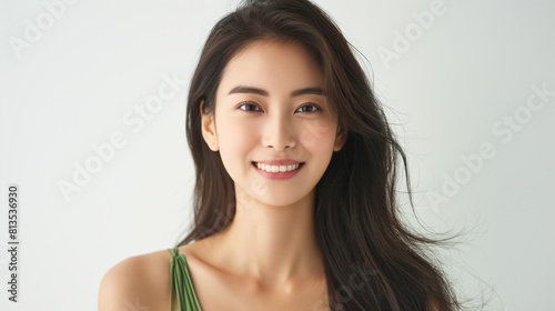 Portrait of a smiling young Asian woman with dark hair on a neutral background.