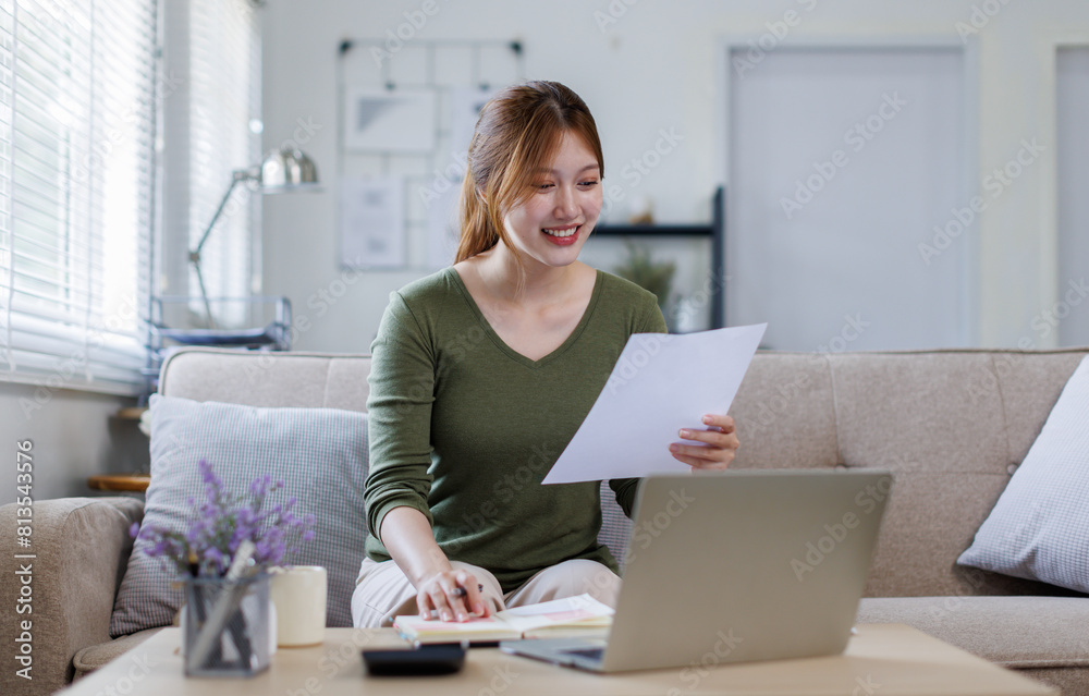 Asian business woman working on a laptop on couch, tax, accounting, statistics and analytical research concept. Asian business woman working on a laptop on couch, tax, accounting, statistics and analytical research concept.