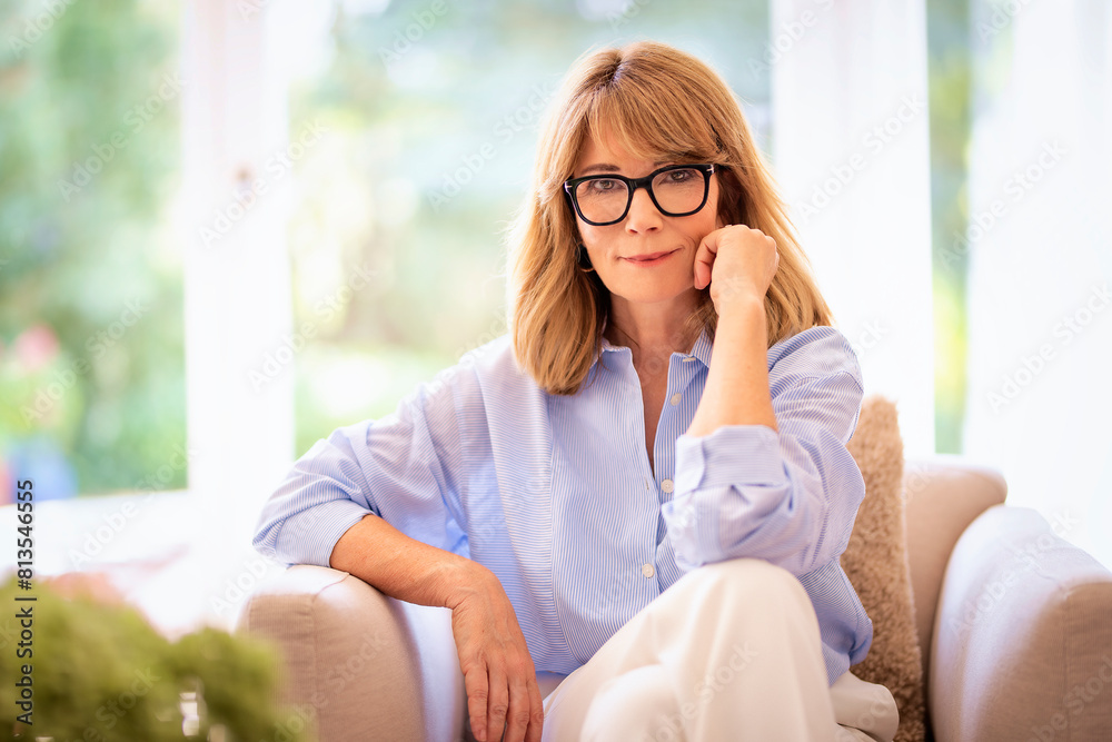 Portrait of blond haired attractive woman sitting in an armchair at home Portrait of blond haired attractive woman sitting in an armchair at home