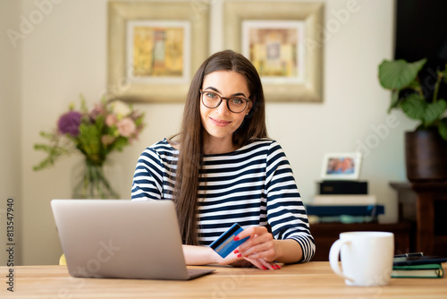 Woman sitting at home and using laptop and credit card and banking online © sepy