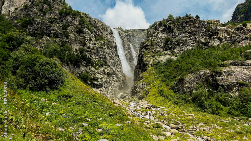 Majestic mountain waterfall cascading through rocky terrain surrounded by lush greenery, ideal for nature, travel themes, and International Mountain Day