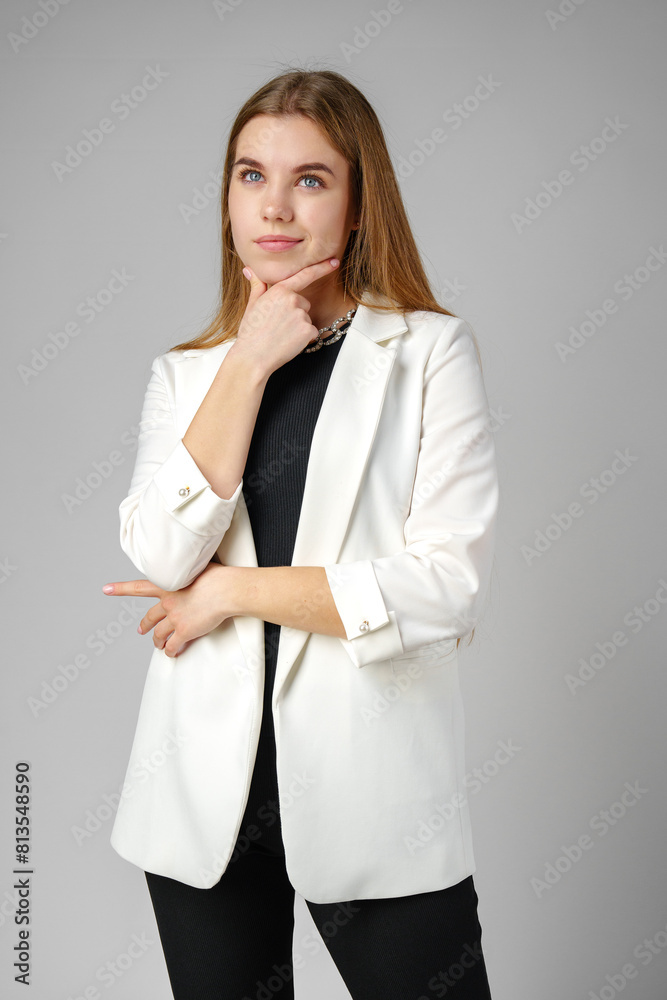 Thoughtful Young Woman in a Stylish White Blazer Posing on gray background Thoughtful Young Woman in a Stylish White Blazer Posing on gray background