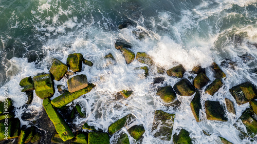 Aerial view of coastal defenses with moss-covered tetrapods and groynes against eroding waves, suitable for environmental studies and World Oceans Day photo