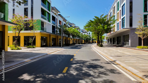 Sunny urban street with modern colorful apartment buildings, empty road with trees, concept of urban development and real estate