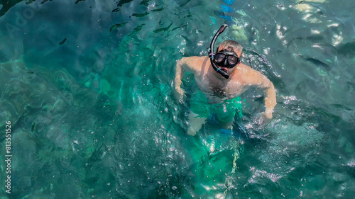 Caucasian male snorkeler floating in clear turquoise waters, summer vacation concept, related to World Oceans Day and beach tourism