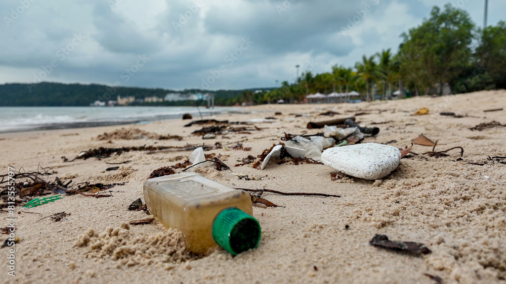 Plastic pollution on a sandy beach with discarded bottle and debris, highlighting environmental concerns, related to Earth Day and World Oceans Day Plastic pollution on a sandy beach with discarded bottle and debris, highlighting environmental concerns, related to Earth Day and World Oceans Day