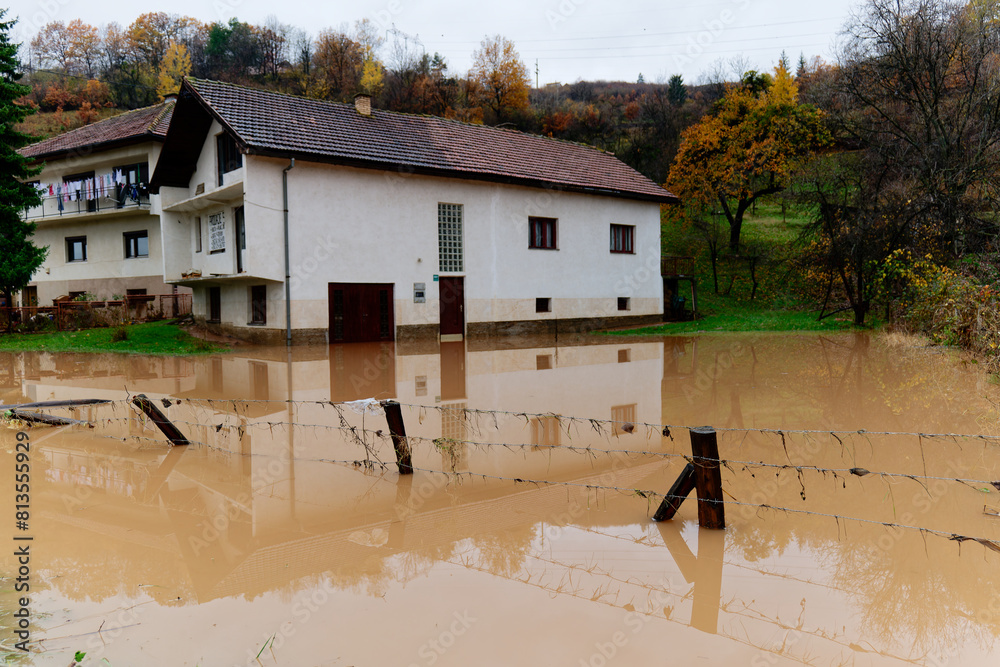 Torrential rain causes flash floods in residential areas. House surrounded by water. Plantation and crops on a green house destroyed by floods. Climate change. Heavy rainfall consequences.