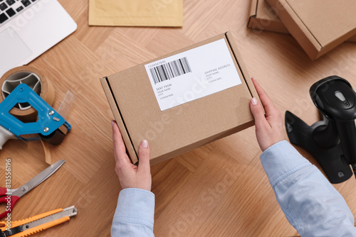 Post office worker packing parcel at wooden table, top view © New Africa