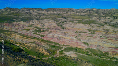Aerial view of colorful, stratified rock formations in a desert landscape, ideal for geology and Earth Day-related themes