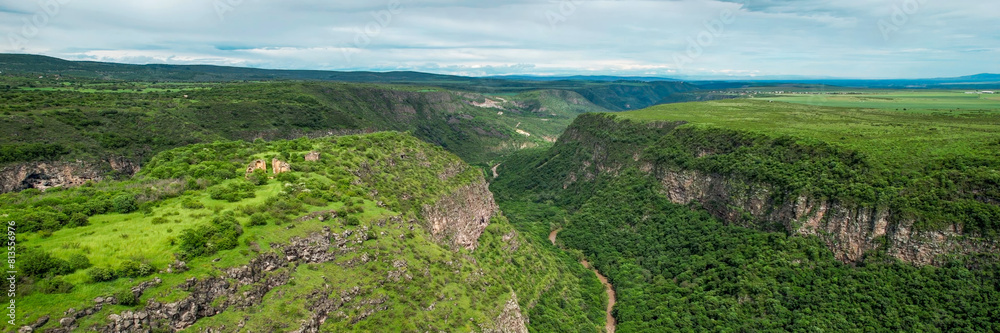 Aerial view of a lush green canyon with a winding river, ideal for themes related to ecotourism, Earth Day, and outdoor adventure travel